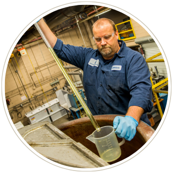 Hazardous waste metals reclamation technician taking sample from electroplating solution